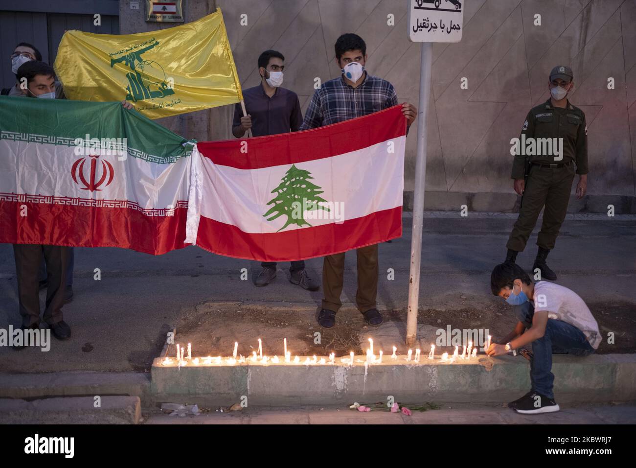 An Iranian boy wearing a protective face mask lights candle on a street-side in front of the Lebanon Embassy in central Tehran, as a symbol of the Iranian people's sympathy for the victims of the recent explosions in Beirut, on August 5, 2020. (Photo by Morteza Nikoubazl/NurPhoto) Stock Photo