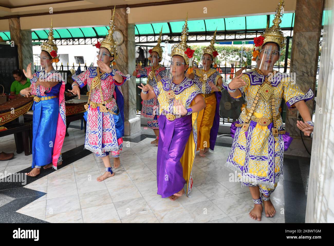 Traditional Thai dancers wearing face shields perform at the Erawan Shrine on August 6, 2020 in Bangkok, Thailand. (Photo by Vachira Vachira/NurPhoto) Stock Photo