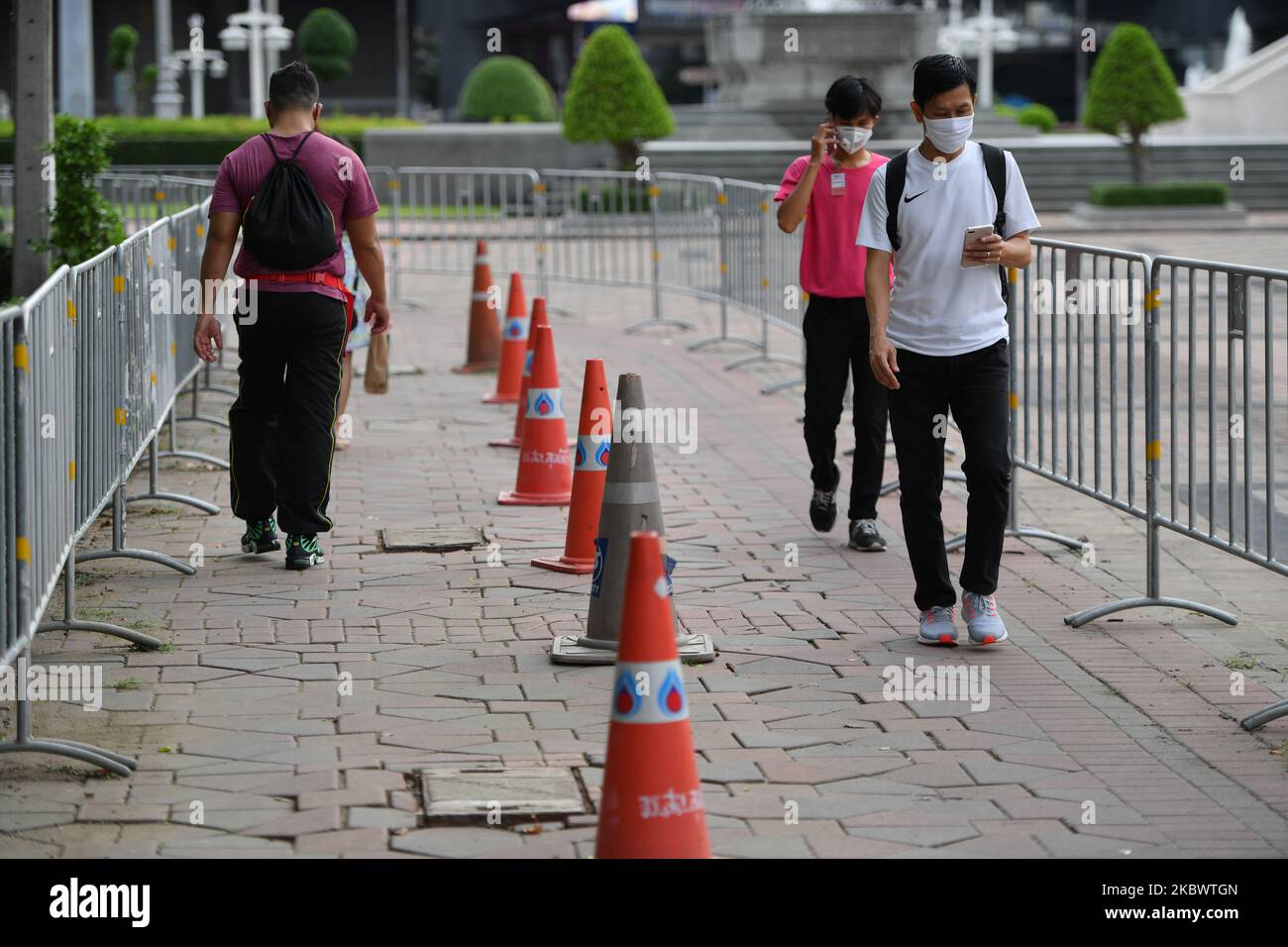 Pedestrians wearing face masks walk to entering a Lumpini public park on August 6, 2020 in Bangkok, Thailand. (Photo by Vachira Vachira/NurPhoto) Stock Photo