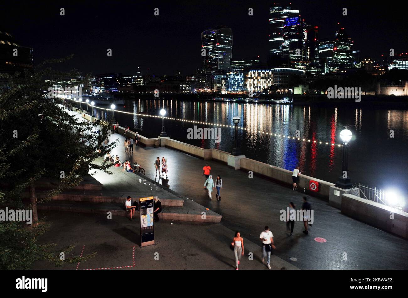 People walk along a footpath beside the River Thames, opposite the ...