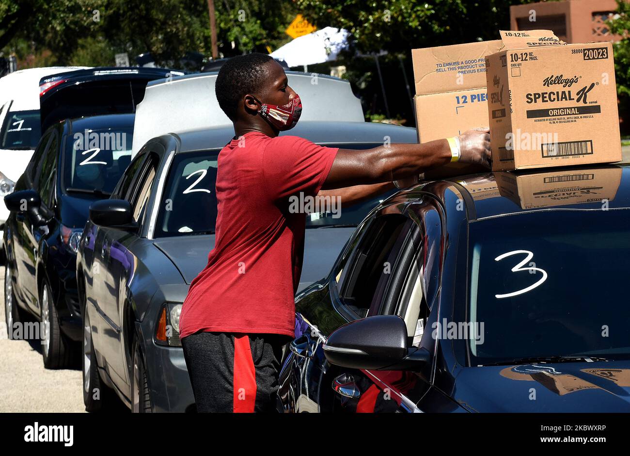 A volunteer places boxes of food from the Second Harvest Food Bank of Central Florida on the roof of a car at a food distribution event at Carter Tabernacle Christian Methodist Episcopal Church on August 8, 2020 in Orlando, Florida. Food Banks in the Orlando area face continued demand as unemployment due to the COVID-19 pandemic persists. (Photo by Paul Hennessy/NurPhoto) Stock Photo