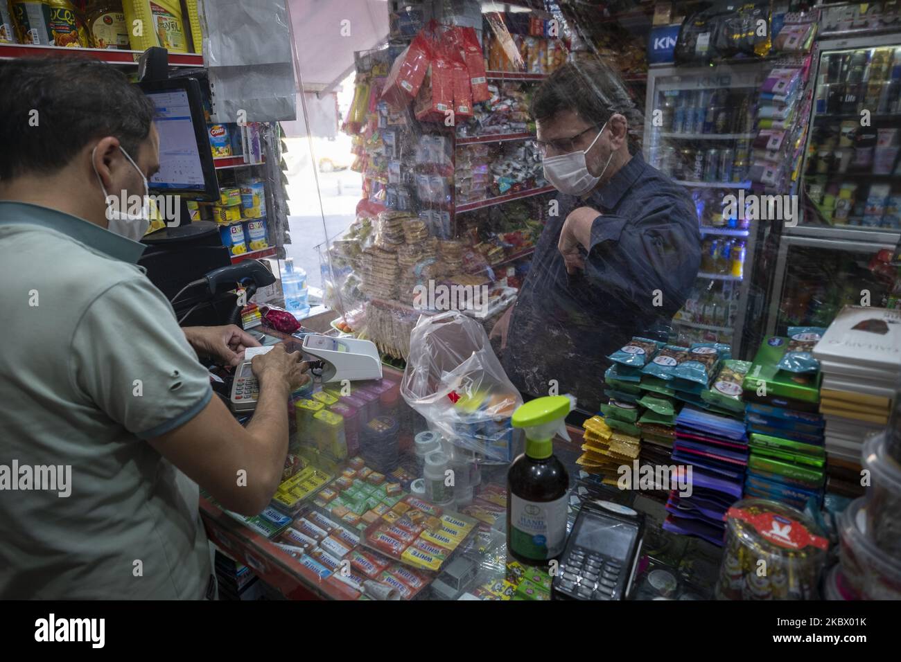 An Iranian man wearing a protective face mask stands behind a divider while shopping at a local supermarket in Tehran’s business district, following the new coronavirus (COVID-19) outbreak in Iran. (Photo by Morteza Nikoubazl/NurPhoto) Stock Photo