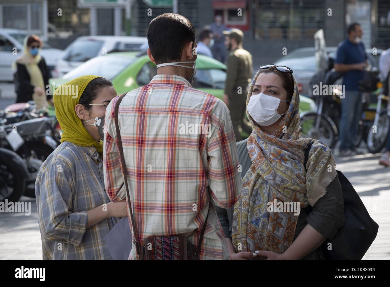 An Iranian man and two women wearing protective face masks speak with each other while standing on a street-side in Tehran’s business district, following the new coronavirus (COVID-19) outbreak in Iran. (Photo by Morteza Nikoubazl/NurPhoto) Stock Photo