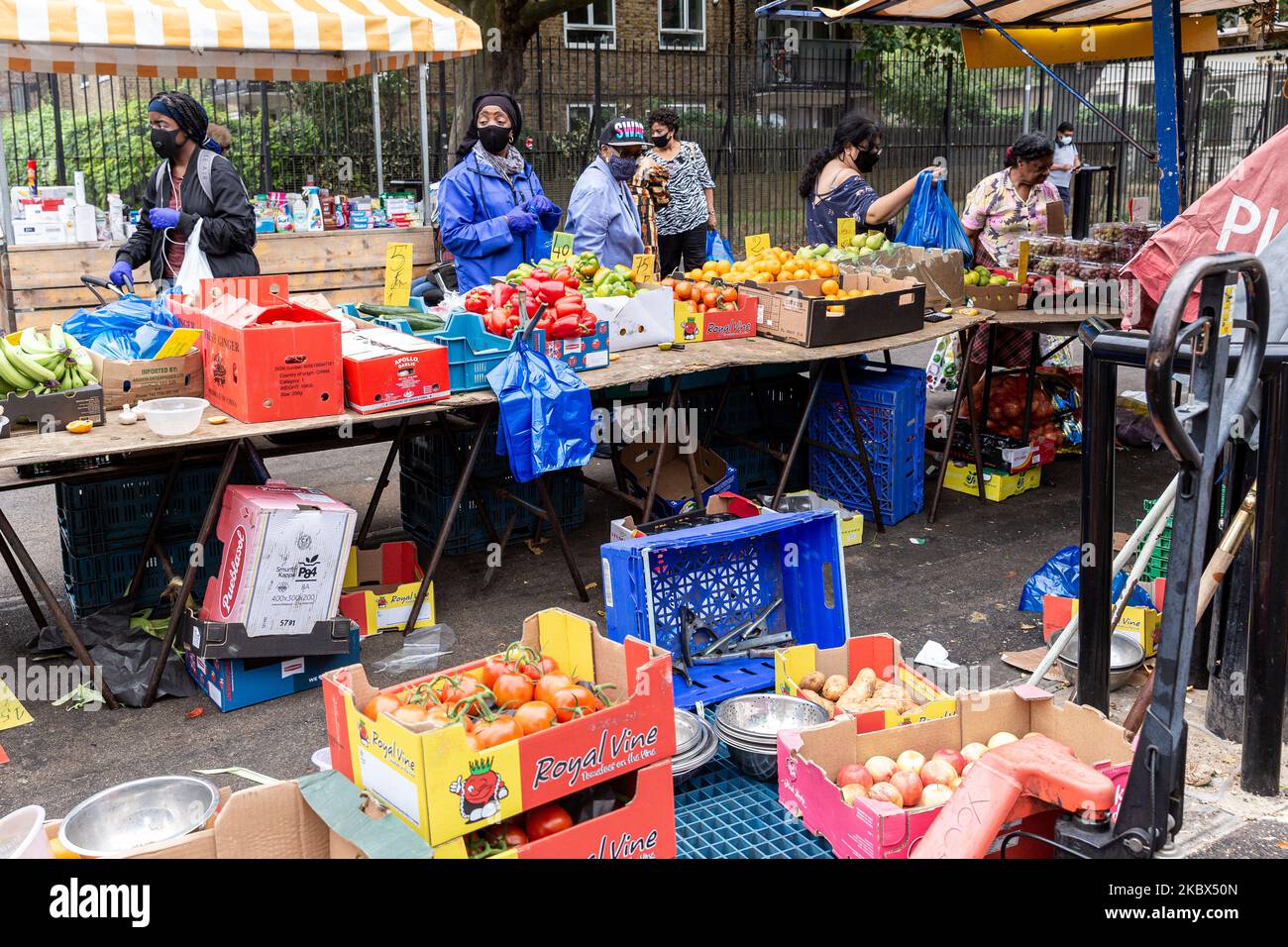 Shoppers in protective face masks are seen walking past a market stand