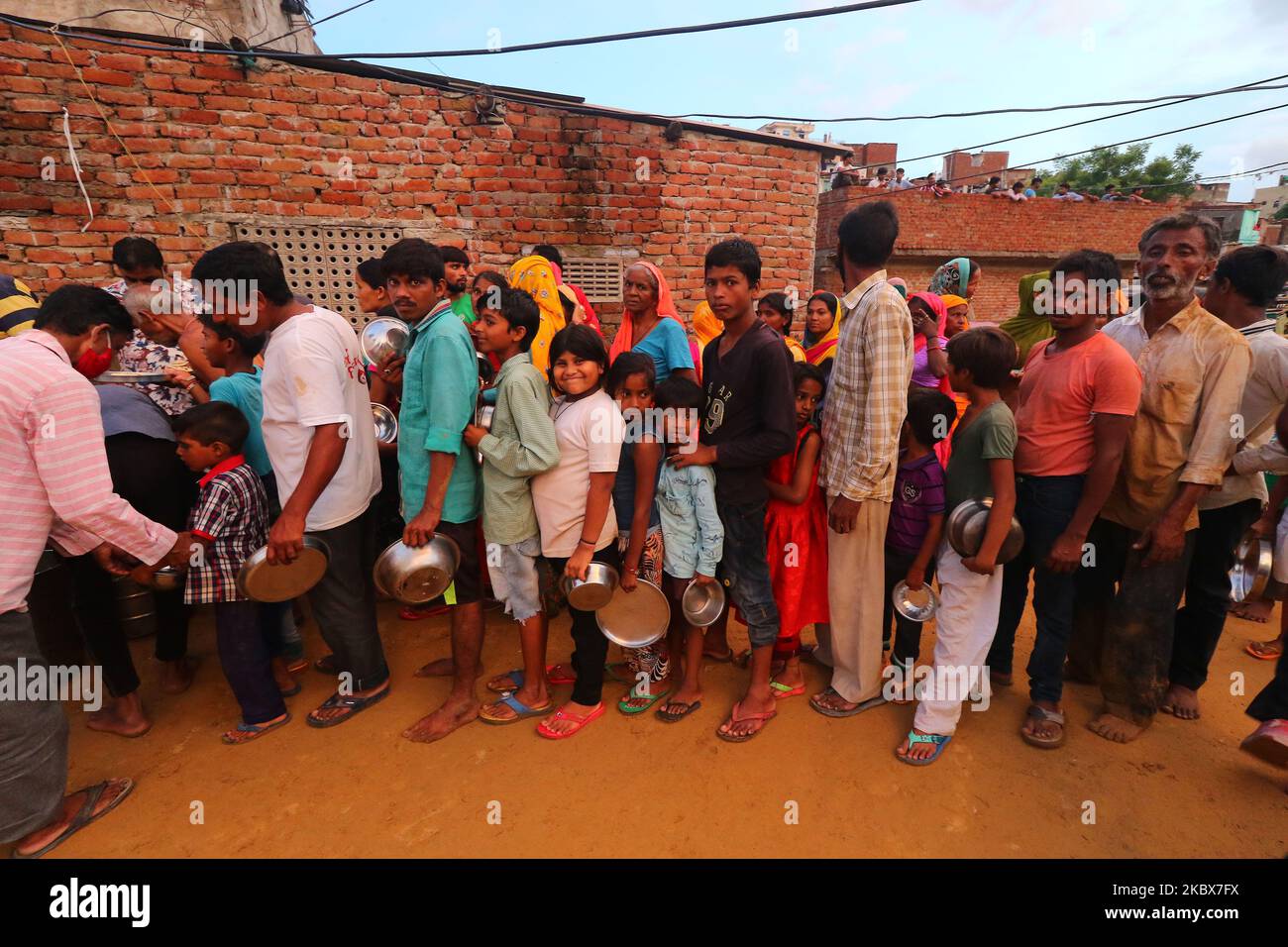 People stand in queue as Rashtriya Sawam Sangh (RSS) members distribute food at landslide affected areas after the following heavy rainfall at Sundar Nagar Ganesh Vihar colony,Lal Dungari , in Jaipur, Rajasthan, India, Aug 16,2020.(Photo by Vishal Bhatnagar/NurPhoto) Stock Photo