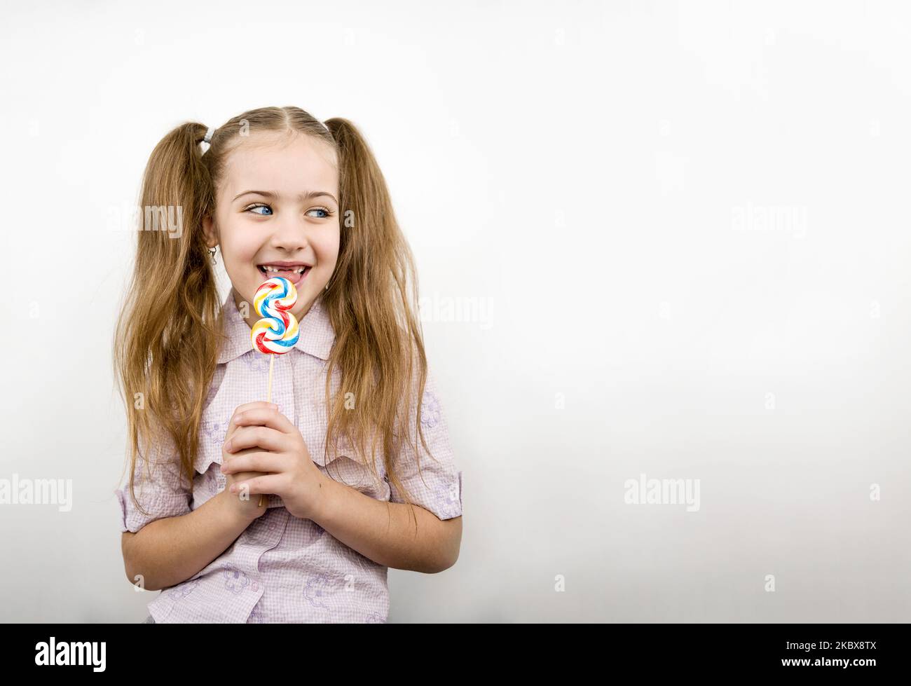 Beautiful girl with blue eyes eating lollipop isolated on white Stock Photo