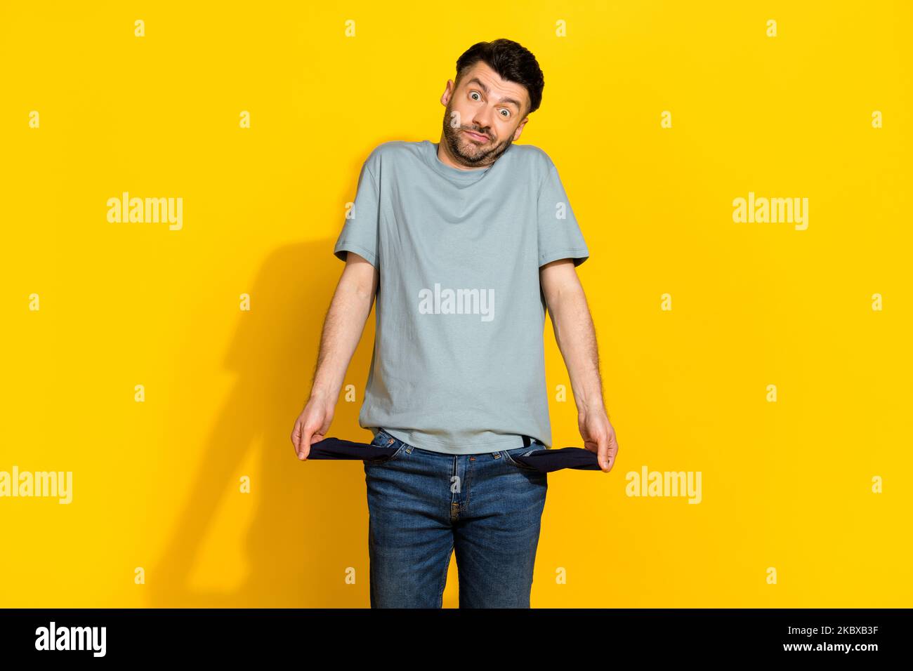 Photo of young funny excited stressed man frustrated confused problems showing his empty pockets