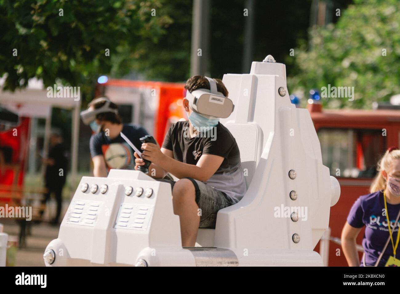 a kid with a face mask tries out a VR simulation of carnival kids ride ...