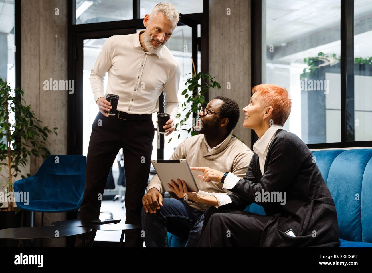 Two multiracial colleagues talking and using cellphone while working in office Stock Photo