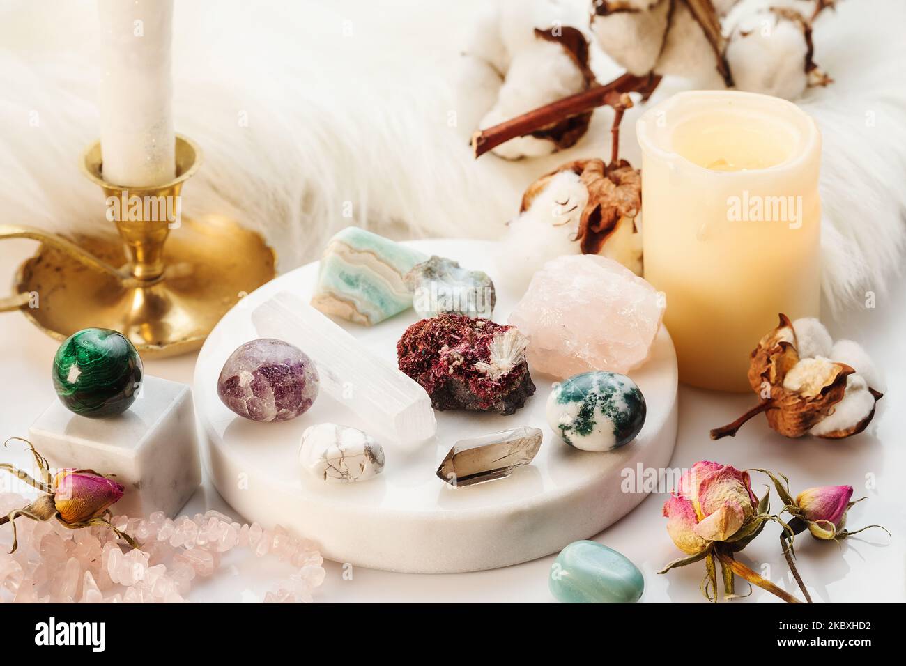 Minerals Collection on White Marble Stand with Burning Candles and Dry Flowers. Healing Stones for Wicca Witchcraft Practice on White Marble Stand Stock Photo