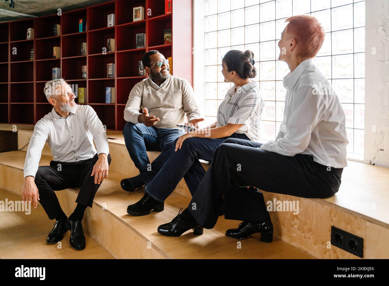 Multiracial colleagues talking and smiling while working in office Stock Photo