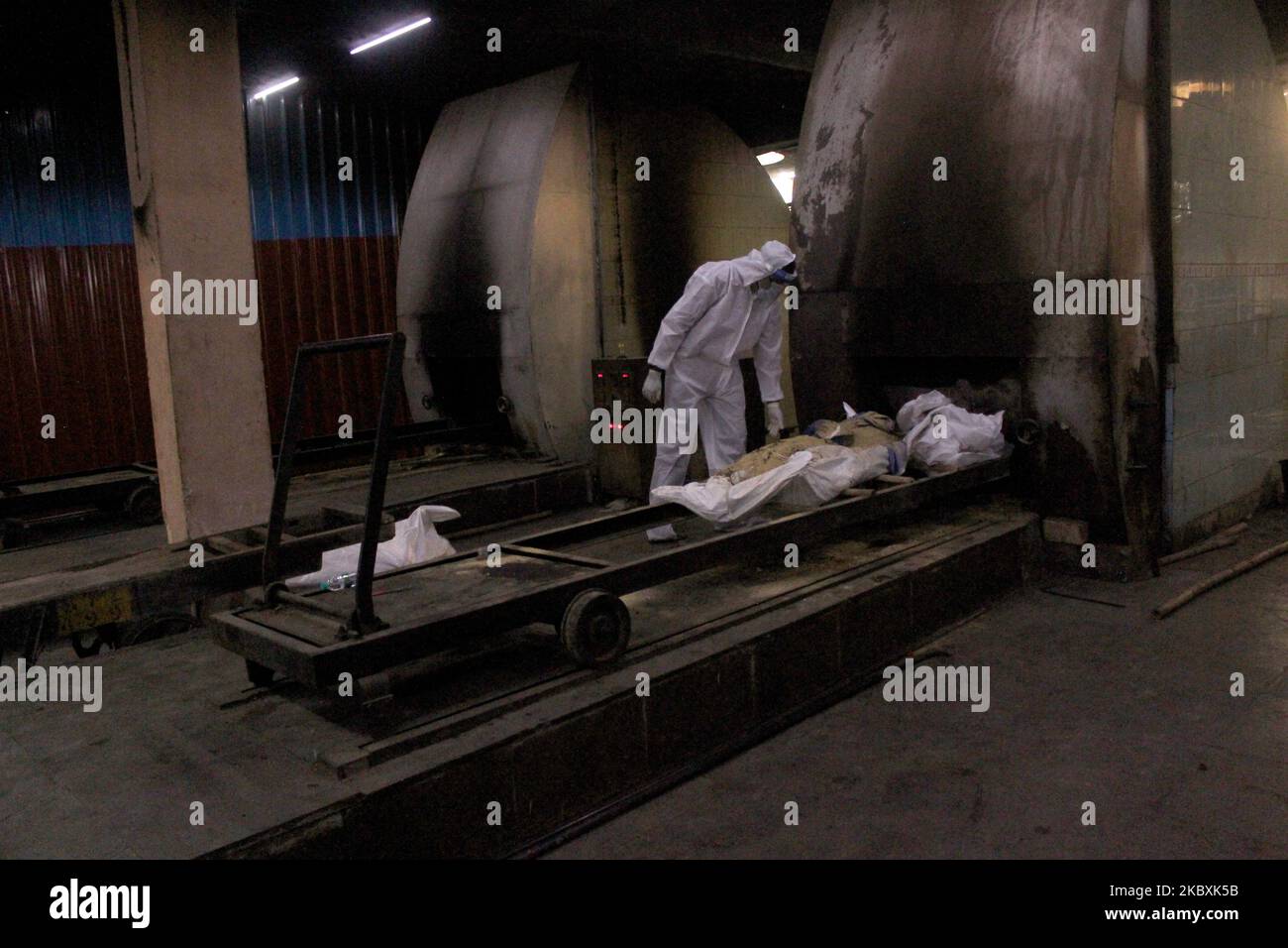 Healthcare workers along with family member wearing Personal Protective Equipment (PPE) place the body of a person who died from the COVID-19 coronavirus before the cremation in a furnace at the Nigambodh Ghat cremation ground, in New Delhi, India on August 26, 2020. (Photo by Mayank Makhija/NurPhoto) Stock Photo