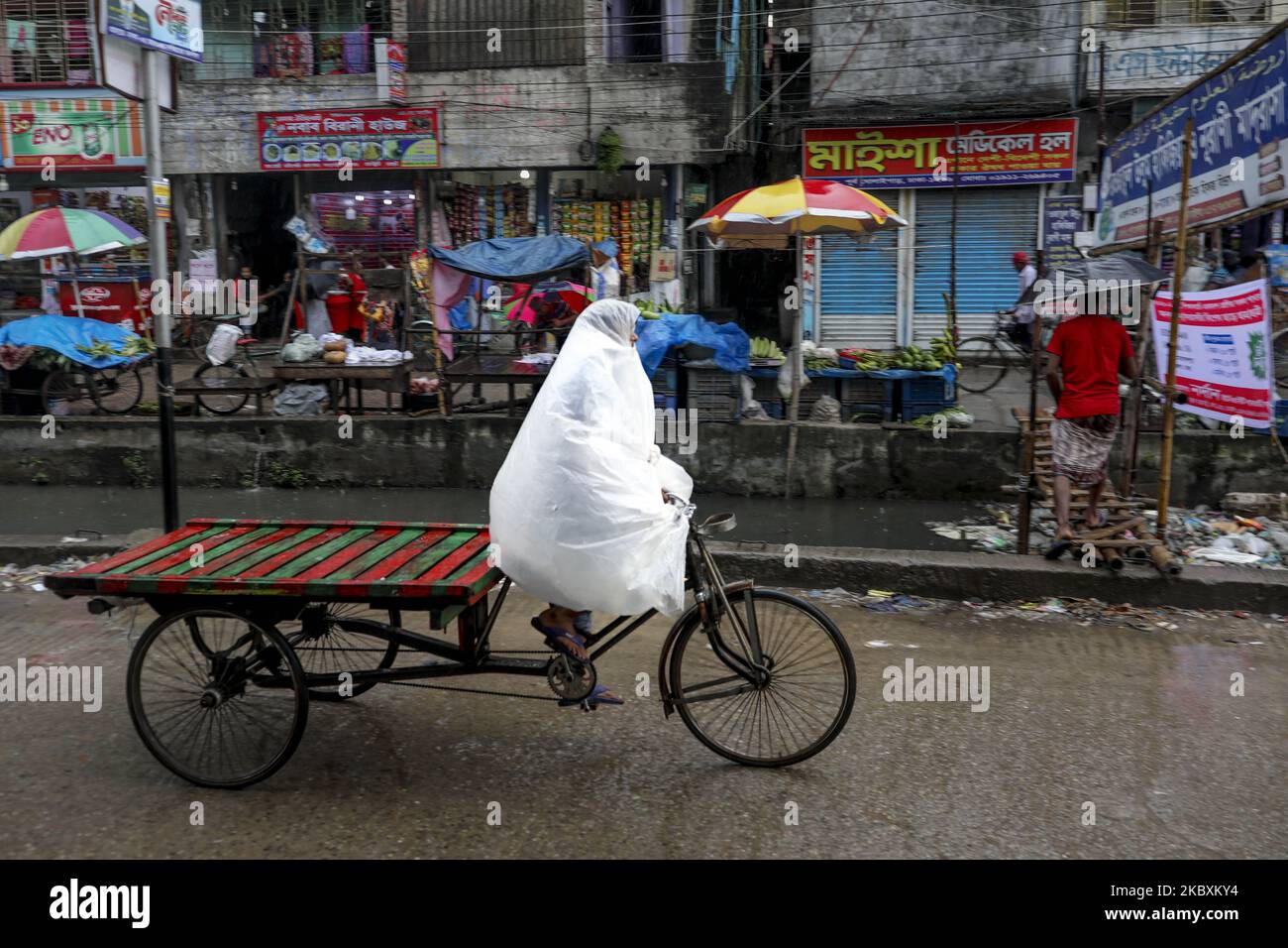 A Rickshawala cover-up with polythene save her from rain in Dhaka Bangladesh on August 27, 2020. (Photo by Kazi Salahuddin Razu/NurPhoto) Stock Photo