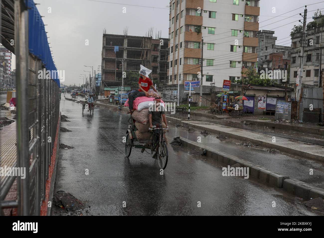 Rickshawala and passenger cover-up with polythene save her from rain in Dhaka Bangladesh on August 27, 2020. (Photo by Kazi Salahuddin Razu/NurPhoto) Stock Photo