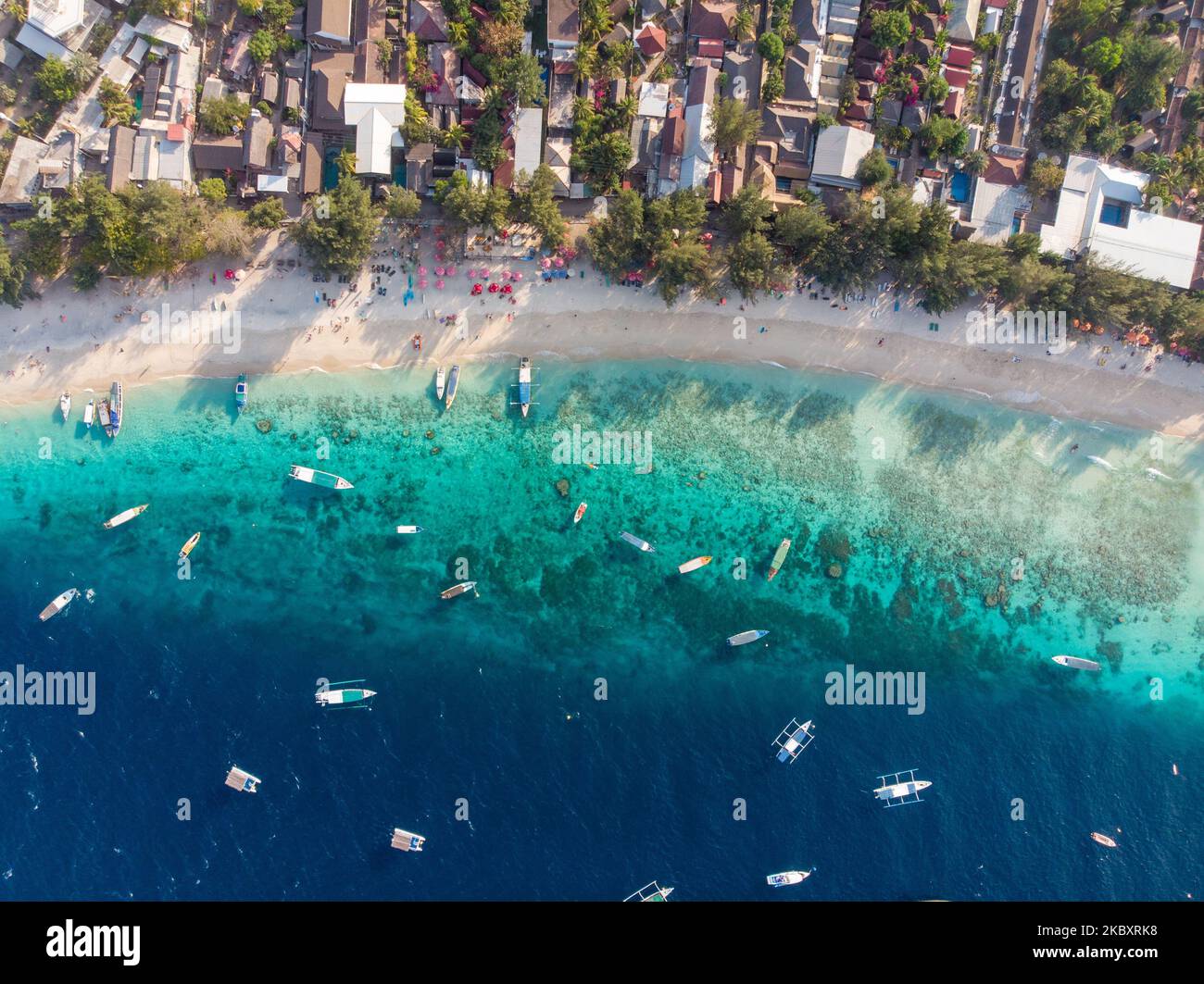 An aerial view of a coastal town with a sandy beach and boats in a bay ...