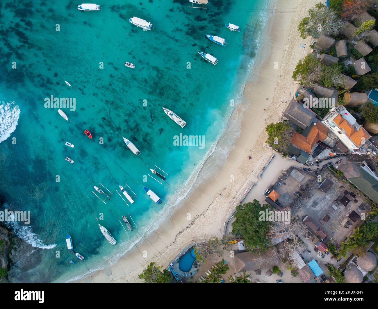 An aerial view of a coastal town with a sandy beach and boats in a bay ...