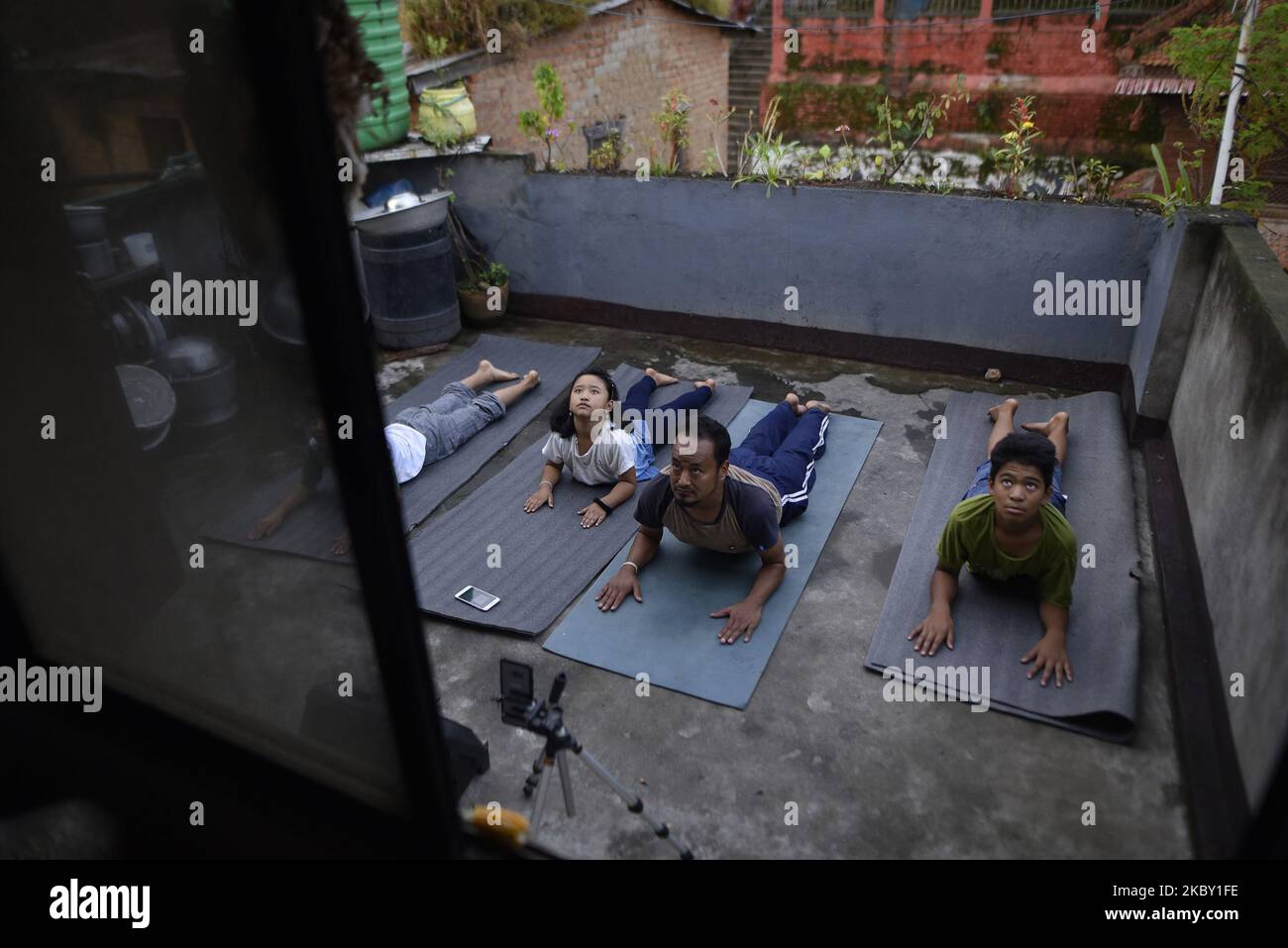 RAJMAN MAHARJAN a Yoga Practitioner along with his family members practicing Yoga Positions in the roof of house after the three district administrations have enforced prohibitory order lockdown in the Kathmandu valley due to rapid increase in the number of COVID-19 cases at Kirtipur, Kathmandu, Nepal on Wednesday, September 02, 2020. (Photo by Narayan Maharjan/NurPhoto) Stock Photo