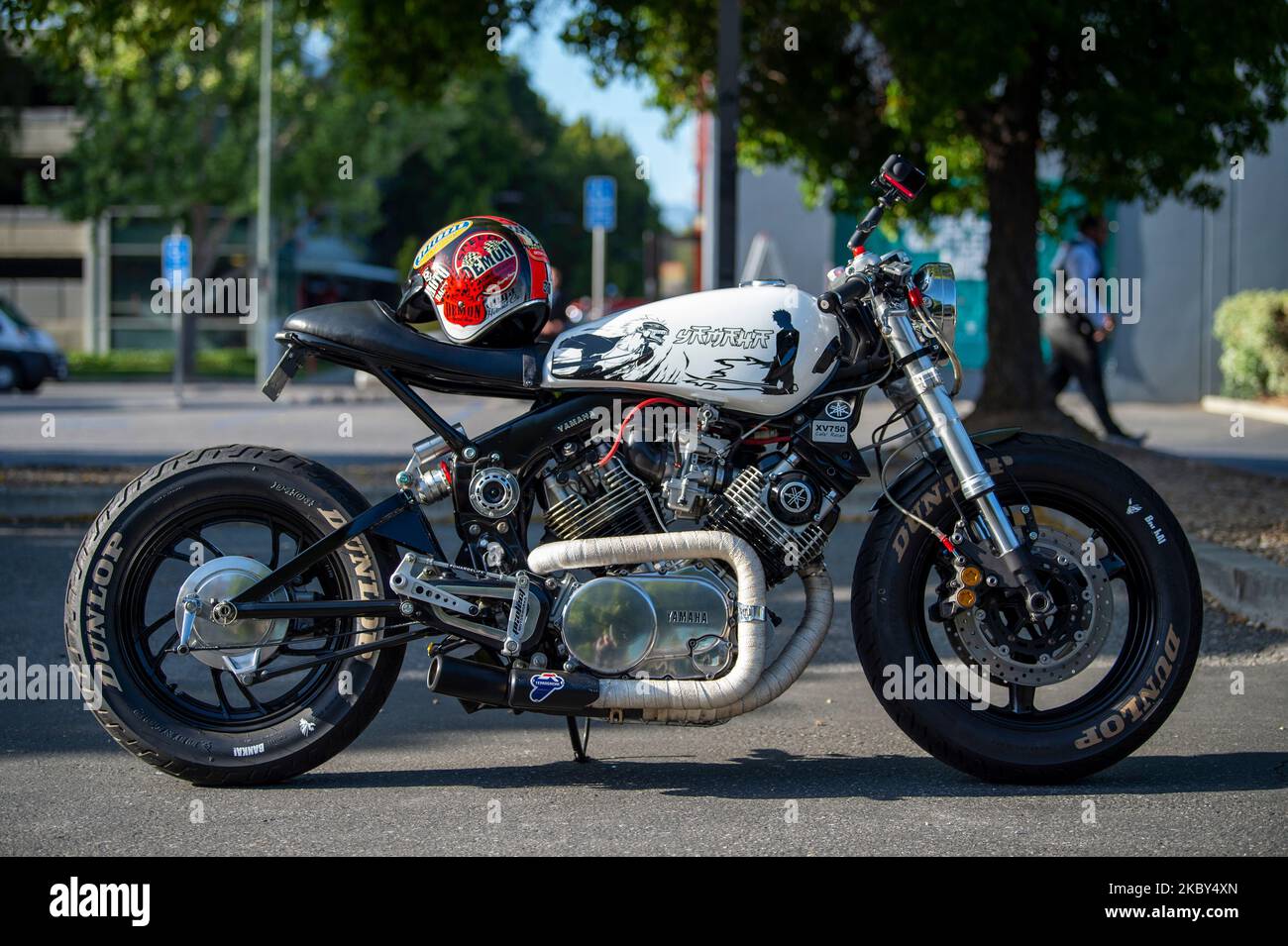 Covered Rims Motorcycle Cafe Racer A custom cafe racer motorcycle parked in a lot with a helmet on the ...