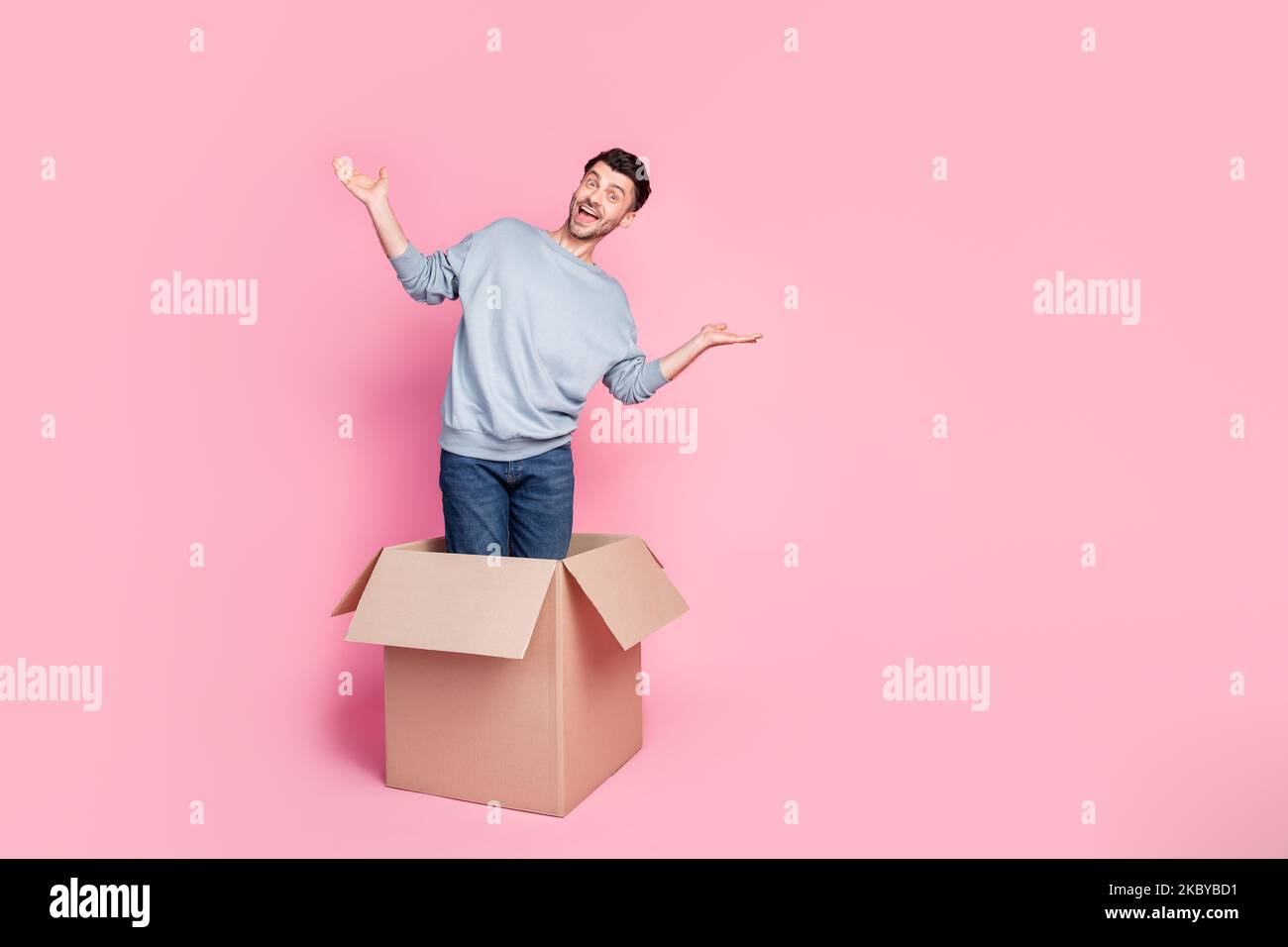 Full size photo of handsome young guy stand carton box raise hands