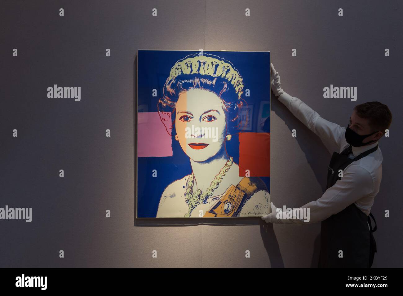 (EDITOR'S NOTE: Editorial use only) A staff member presents 'Queen Elizabeth II' from: Reigning Queens (Royal Edition) screenprint in colours with diamond dust, 1985, by Andy Warhol (estimated sale price ?100,000-150,000) during a press preview of 'Prints & Multiples: Modern to Pop' online sale at Christie's on September 09, 2020 in London, England. The sale, taking place from 10 - 22 September, will showcase classic modern and pop prints, including works from 20th century icons such as Henri Matisse, Pablo Picasso, Francis Bacon, David Hockney, Andy Warhol, Roy Lichtenstein and Keith Haring.  Stock Photo