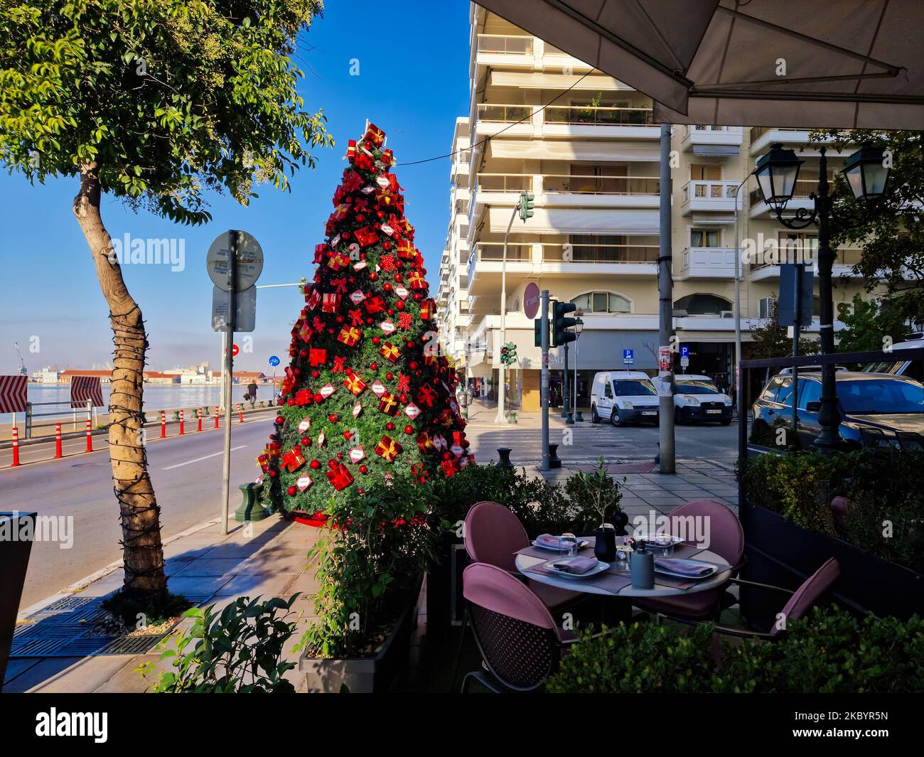 Day view of early holiday decorations by the main road. Festive installments of Christmas tree at Nikis street next to an outdoor seating area in Thessaloniki, Greece. Stock Photo