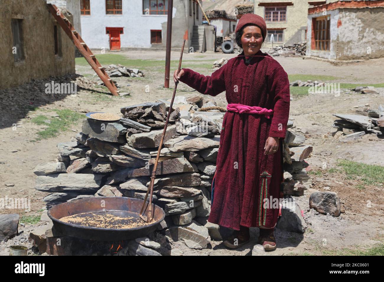 Ladakhi woman roasting barley outside her home in Zanskar, Ladakh