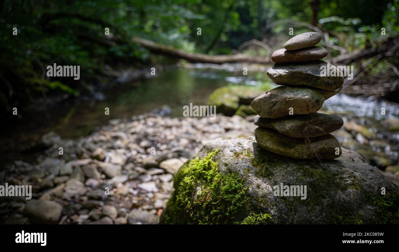 A closeup of stacked rocks in background of flowing river Stock Photo