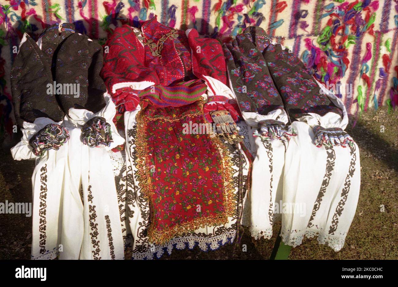 Hunedoara County, Romania, 2003. Different authentic traditional women costumes from the region of Padureni. The red colored clothing are worn by young women, while the white and grey/ black ones are specific for elderly women. Stock Photo