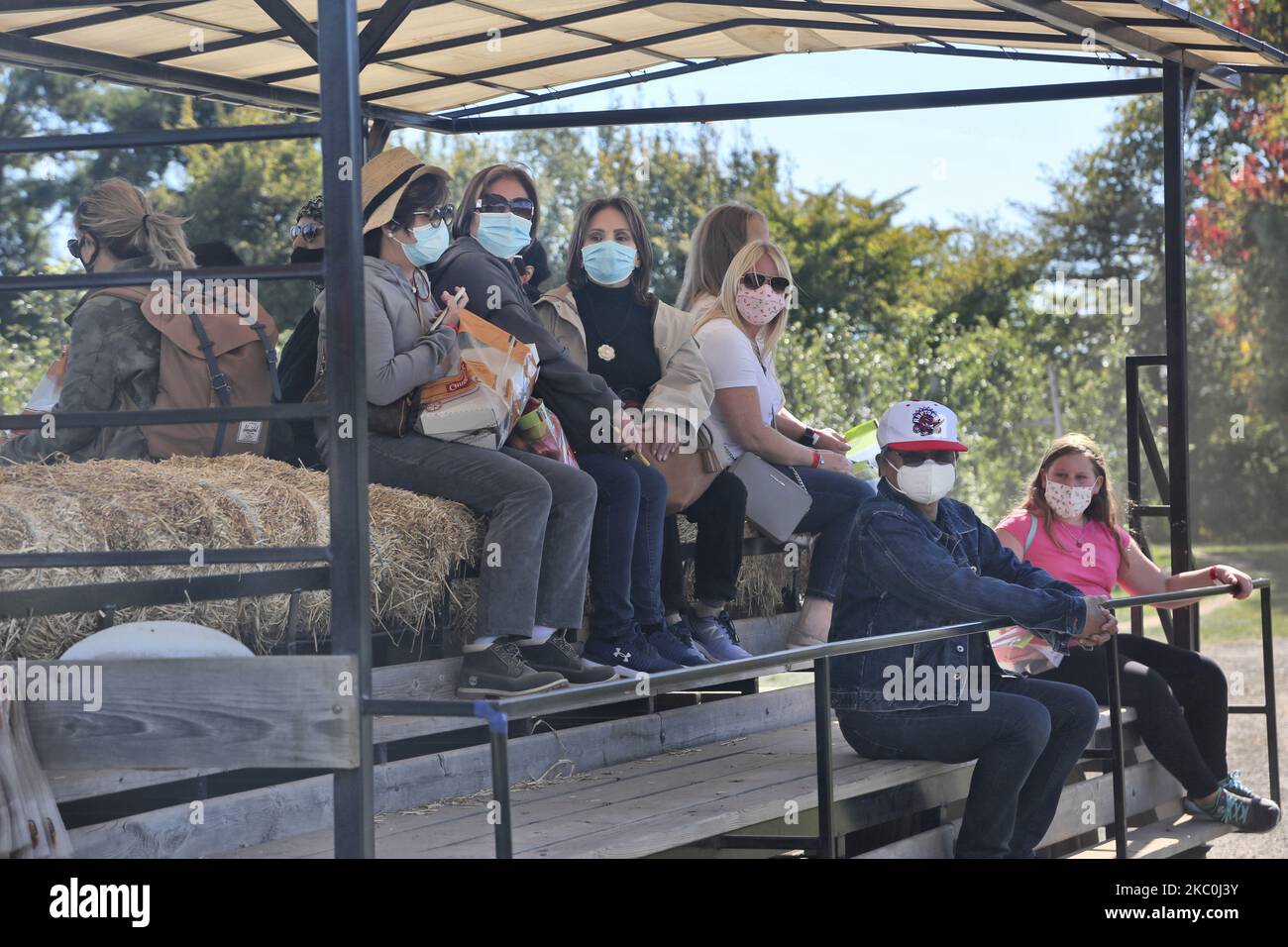 People wear face masks while on a hay ride at an apple farm during the novel coronavirus (COVID-19) pandemic in Milton, Ontario, Canada, on September 20, 2020. (Photo by Creative Touch Imaging Ltd./NurPhoto) Stock Photo