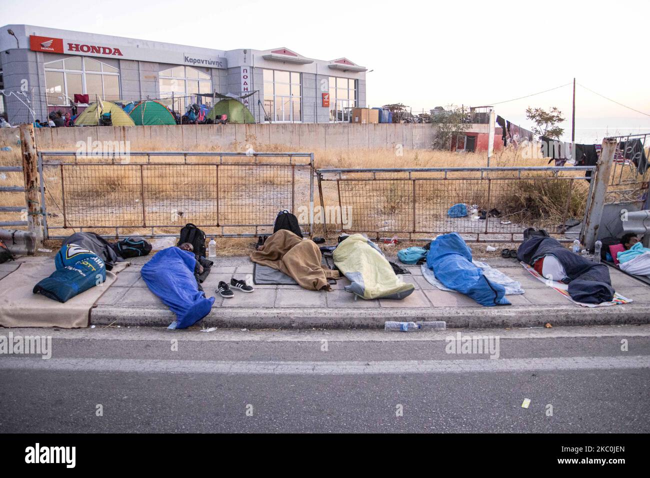 Refugees and migrants sleeping on the streets. Early morning with more than 10.000 Asylum Seekers sleep roadside after the fire in Moria Refugee Camp, the hotspot center for Identification and Registration. Homeless refugees and migrants without any shelter or facilities like toilets or running water live on the road between Mytilene or Mitlini city, the capital of the island and Moria, near Karatepe resulting the main road of the island to close, in makeshift tents as there was no place to accommodate them at that time, later the new temporary Kara Tepe or Mavrovouni Refugee camp was created. Stock Photo