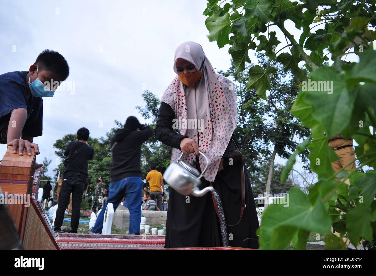 A woman and her child are watering her family's grave at the mass grave of victims of the earthquake, tsunami and liquefaction, Poboya Village, Palu City, Central Sulawesi Province, Monday, September 28, 2020. This is to remember and pray for their families who were victims of the two natural disasters. last year. (Photo by Faldi Muhammad/NurPhoto) Stock Photo