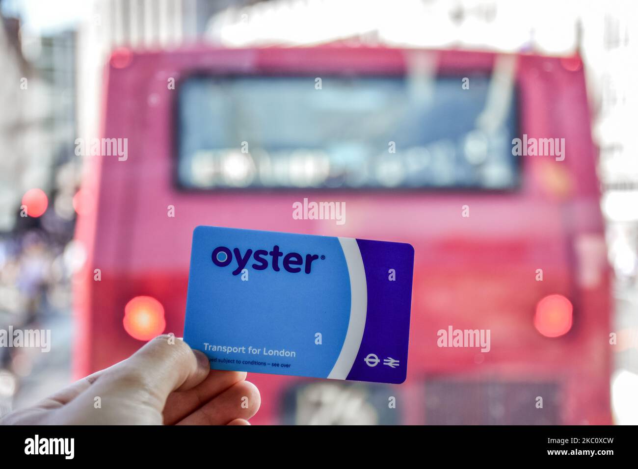 London, England July 07 2017 Hand holding the blue Oyster card behind the red bus