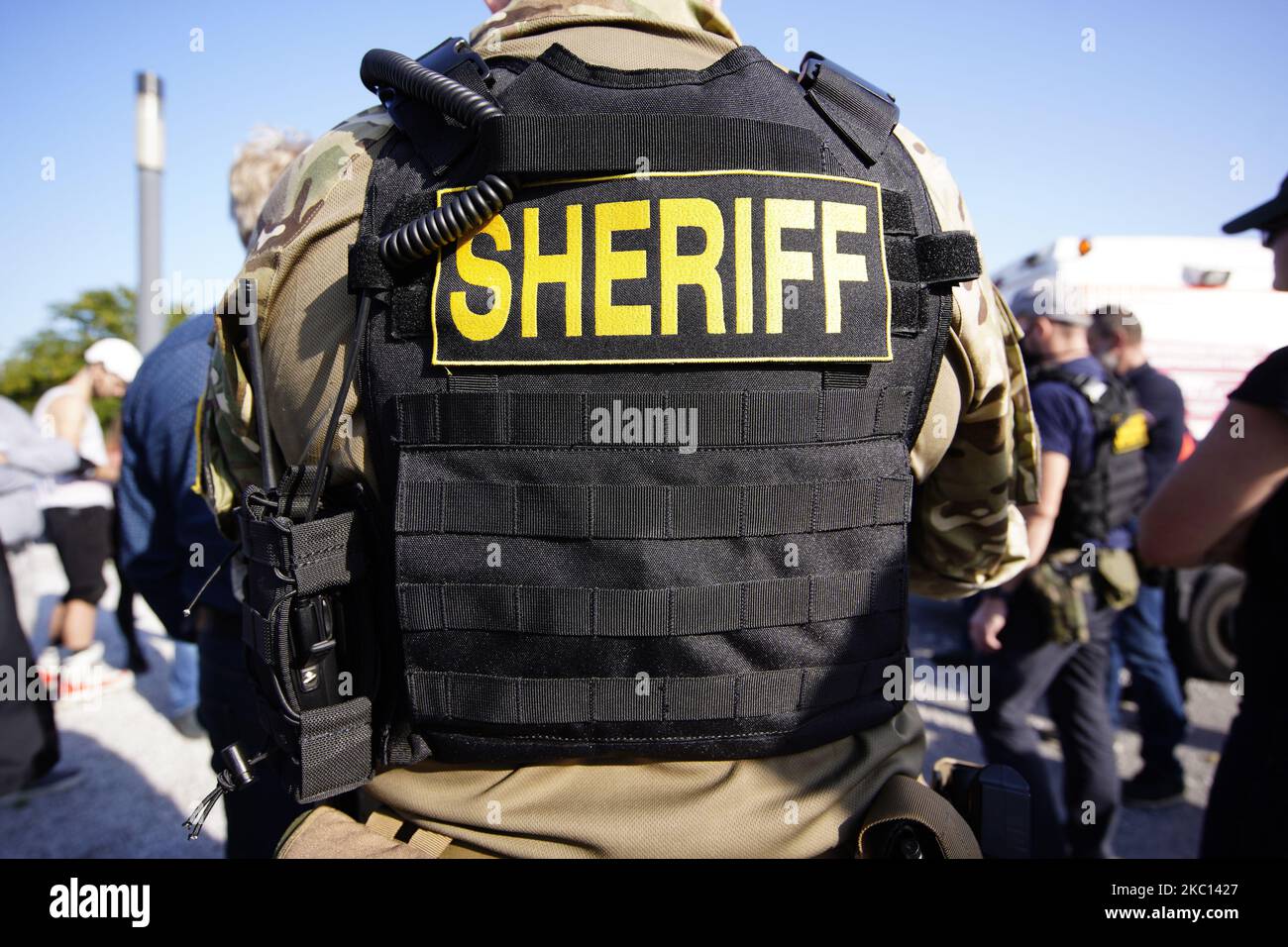 A man weargin tactical gear, a bullet proof vest is seen with the word