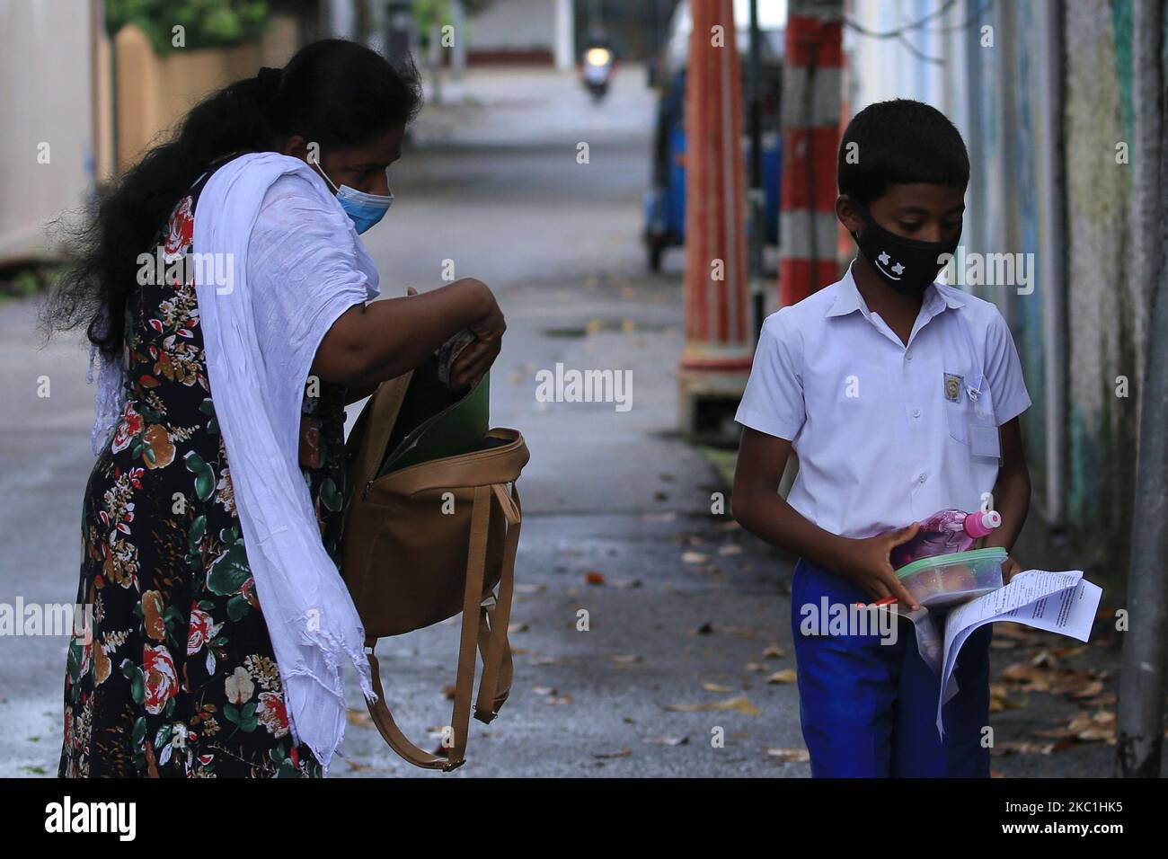 A Sri Lankan student wearing a protective mask heads towards the exam center as his mother (L) checks his bag after handing over the admission papers and food near an examination center for Grade-5 scholarship exam at Colombo, Sri Lanka on 11 October 2020. (Photo by Tharaka Basnayaka/NurPhoto) Stock Photo