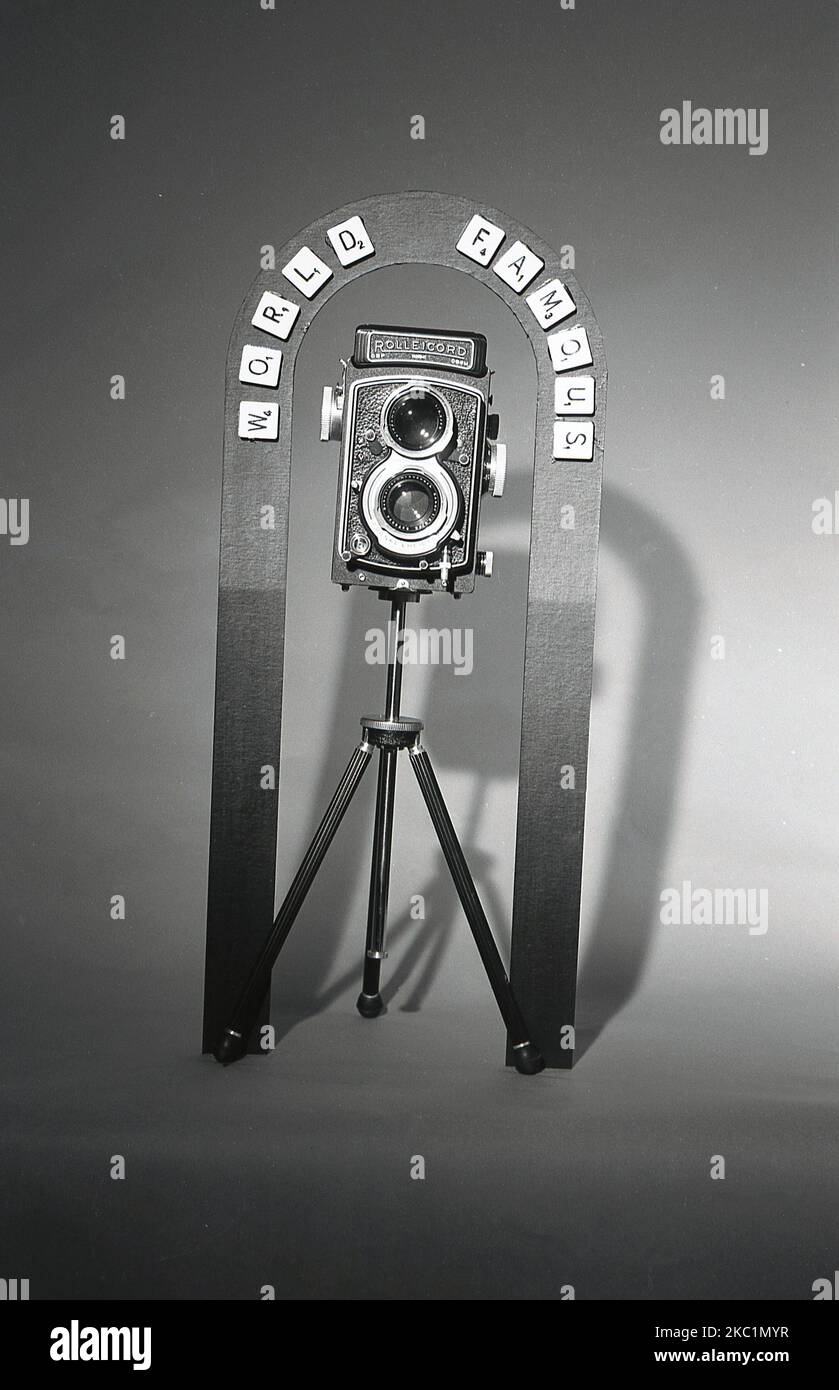 1950s, historical, a twin-reflex camera, a Rolleicord, sat on a tripod. The words 'World Famous' - Scramble letters - are fixed onto a metal surround. The Rolleicord, a medium film format lightweight twin reflex camera, was a simpler, cheaper version of the professional Rolleiflex film-camera and was manufactured, with different models, from 1933 through to 1976. Stock Photo