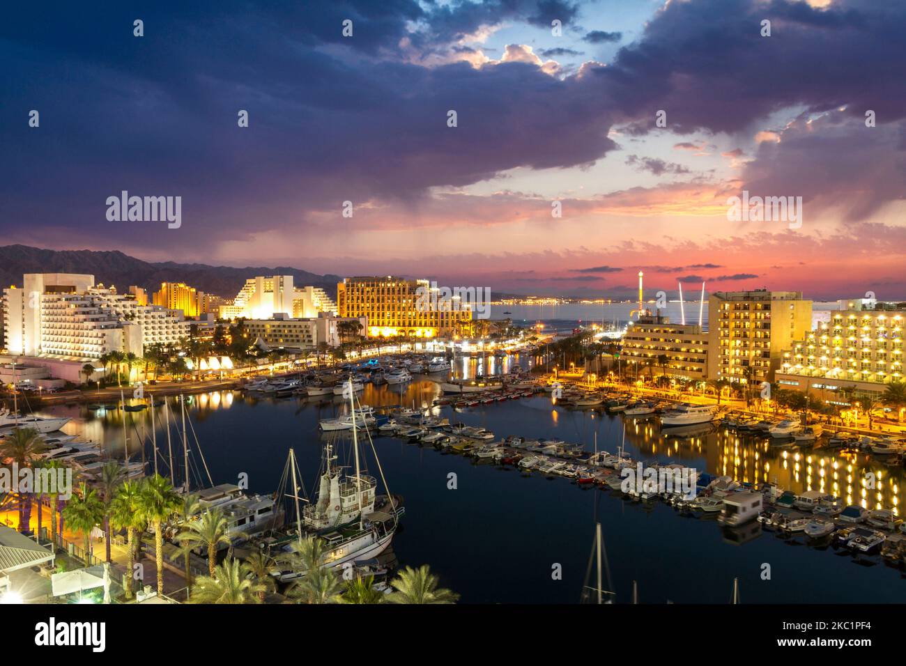Night and evening view of Ships anchoring at eilat marina in front of the red sea, the hotels cityscape and moab mountains at the background, Eilat, I Stock Photo