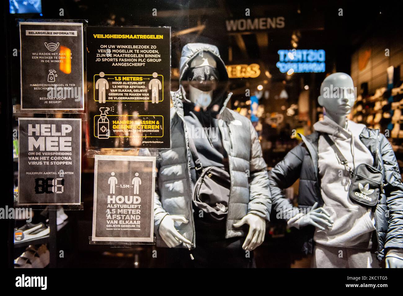 A window clothes store is full of Corona measures warning signs, during