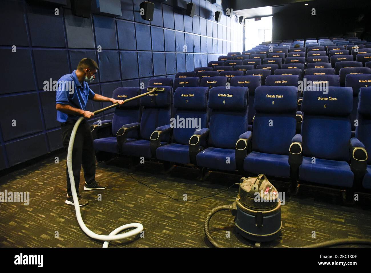 A worker cleaning the seats of a cinema hall as cinemas reopen as part