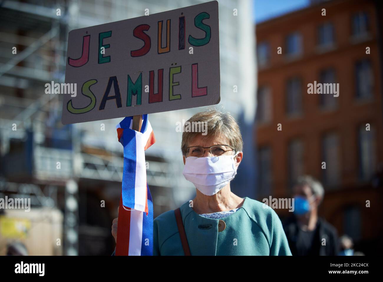 A woman holds a placard reading 'I'm Samuel' with a ribbon at the French colors. After the killing of Samuel Paty, teacher of Geography-History, in Conflans-Sainte-Honorine (Yvelines) on October 16th several thousands of people gathered on the main square of Toulouse, in front of the townhall, the Capitole, to defend freedom of expression and to pay tribute to Samuel. Some people came with a cover of Charlie Hebdo as the teacher has been killed after showing at his pupils the Charlie Hebdo' caricatures of Muhammed. The killer has been killed by French police afterwards. On October 18th, 2020 i Stock Photo