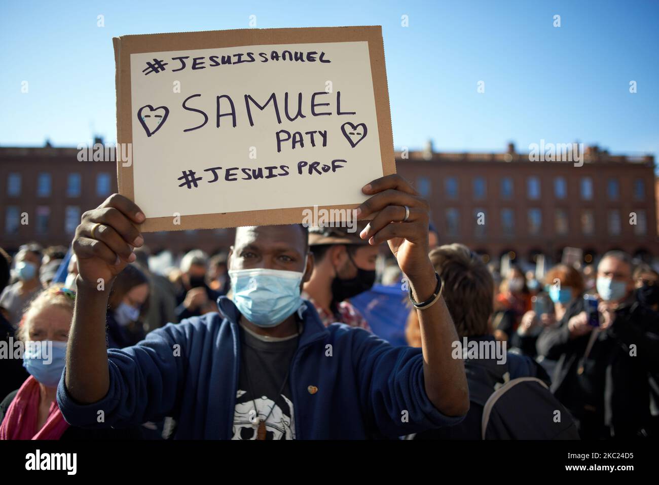 A man holds a placard reading 'I'm Samuel Paty, #Imateacher'. ' with a ribbon at the French colors. After the killing of Samuel Paty, teacher of Geography-History, in Conflans-Sainte-Honorine (Yvelines) on October 16th several thousands of people gathered on the main square of Toulouse, in front of the townhall, the Capitole, to defend freedom of expression and to pay tribute to Samuel. Some people came with a cover of Charlie Hebdo as the teacher has been killed after showing at his pupils the Charlie Hebdo' caricatures of Muhammed. The killer has been killed by French police afterwards. On O Stock Photo