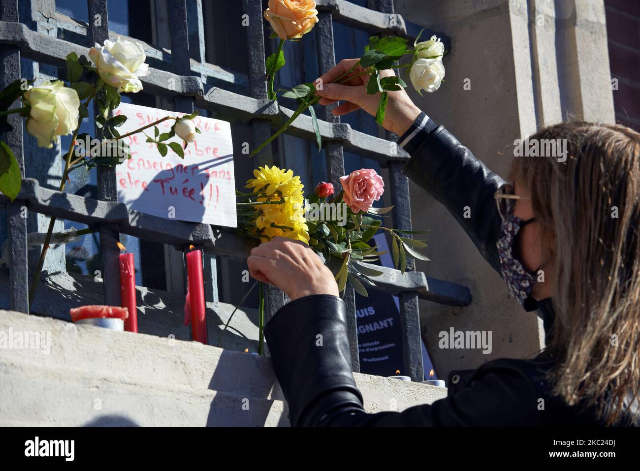 A woman put flowers on an improvised altar to pay tribute to Samuel Paty. After the killing of Samuel Paty, teacher of Geography-History, in Conflans-Sainte-Honorine (Yvelines) on October 16th several thousands of people gathered on the main square of Toulouse, in front of the townhall, the Capitole, to defend freedom of expression and to pay tribute to Samuel. Some people came with a cover of Charlie Hebdo as the teacher has been killed after showing at his pupils the Charlie Hebdo' caricatures of Muhammed. The killer has been killed by French police afterwards. On October 18th, 2020 in Toulo Stock Photo