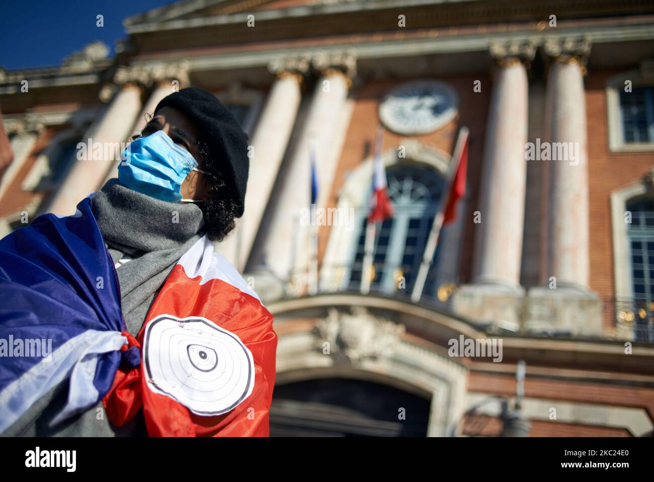 A woman is wrapped in a French flag with a target in front of the townhall of toulouse, the Capitole. After the killing of Samuel Paty, teacher of Geography-History, in Conflans-Sainte-Honorine (Yvelines) on October 16th several thousands of people gathered on the main square of Toulouse, in front of the townhall, the Capitole, to defend freedom of expression and to pay tribute to Samuel. Some people came with a cover of Charlie Hebdo as the teacher has been killed after showing at his pupils the Charlie Hebdo' caricatures of Muhammed. The killer has been killed by French police afterwards. On Stock Photo