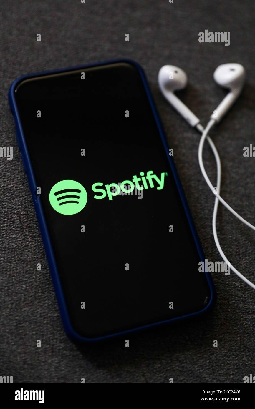 Spotify Logo Displayed On A Phone Screen And Headphones Are Seen In ...