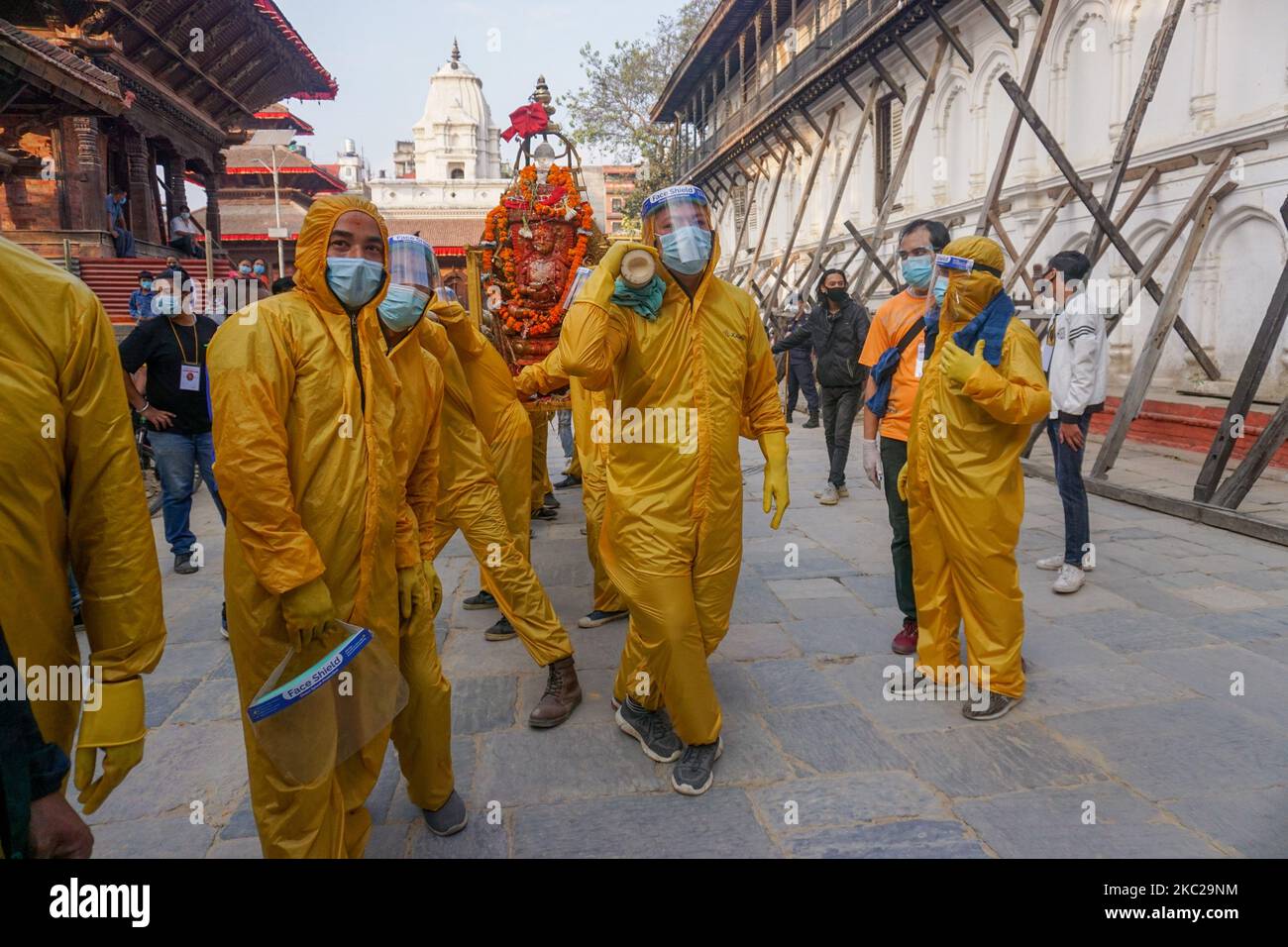 Hindu devotees wearing protective gear carry an idol of deity Pachali