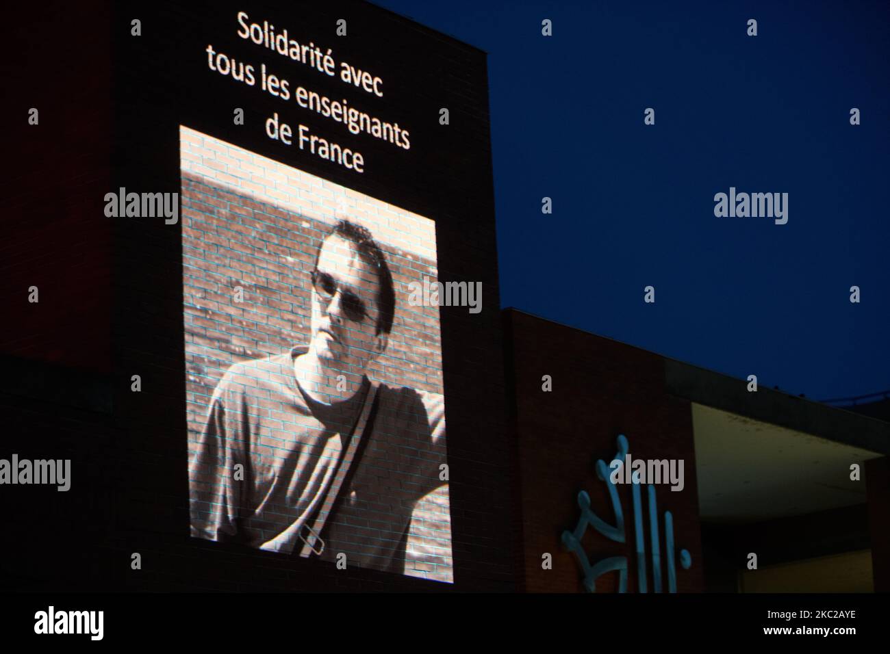A projected picture on the Regional Council building of Samuel Paty reading 'solidarity with all teachers of France'. 'After the killing of Samuel Paty, teacher of Geography-History, in Conflans-Sainte-Honorine (Yvelines) on October 16th, an official homage took place in Toulouse as in Paris or other towns in France. One tribute took place on the Capitole square and the 2nd took place near the Regional Council building. Elected people gathered on the Capitole square and a showing of cartoons on religion took place on the Regional Council building with the head of the Regional council gaves a p Stock Photo