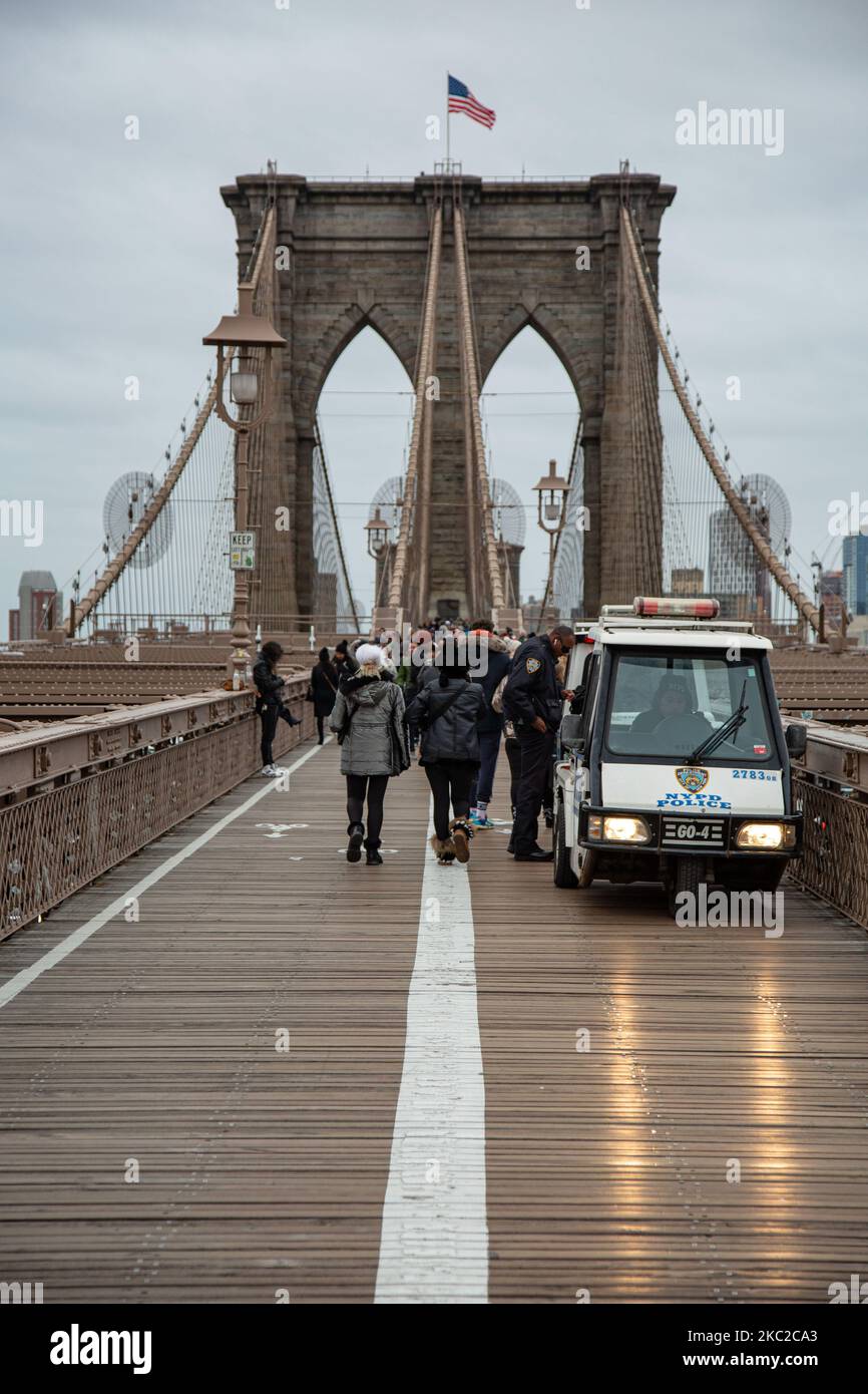The police and people on Brooklyn Bridge in New York City in the United States as seen during a cloudy day with tourists and locals on it. The famous bridge, a landmark for NYC and the United States of America is a hybrid cable stayed suspension bridge spanning the East River between the boroughs of Manhattan and Brooklyn. The historical NY landmark bridge was built between 1869 and 1883. New York, USA on February 13, 2020 (Photo by Nicolas Economou/NurPhoto) Stock Photo