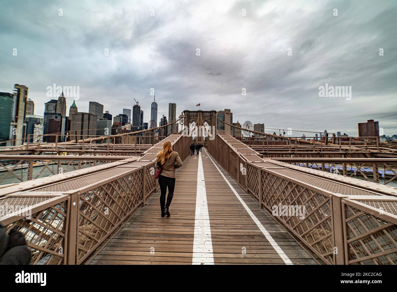 View from the Brooklyn Bridge of Downtown Manhattan. The Brooklyn Bridge in New York City in the United States as seen during a cloudy day with tourists and locals on it. The famous bridge, a landmark for NYC and the United States of America is a hybrid cable stayed suspension bridge spanning the East River between the boroughs of Manhattan and Brooklyn. The historical NY landmark bridge was built between 1869 and 1883. New York, USA on February 13, 2020 (Photo by Nicolas Economou/NurPhoto) Stock Photo