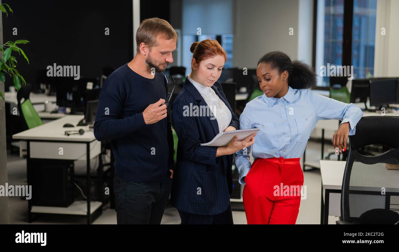 Colleagues discuss paperwork. African young woman, caucasian and red ...