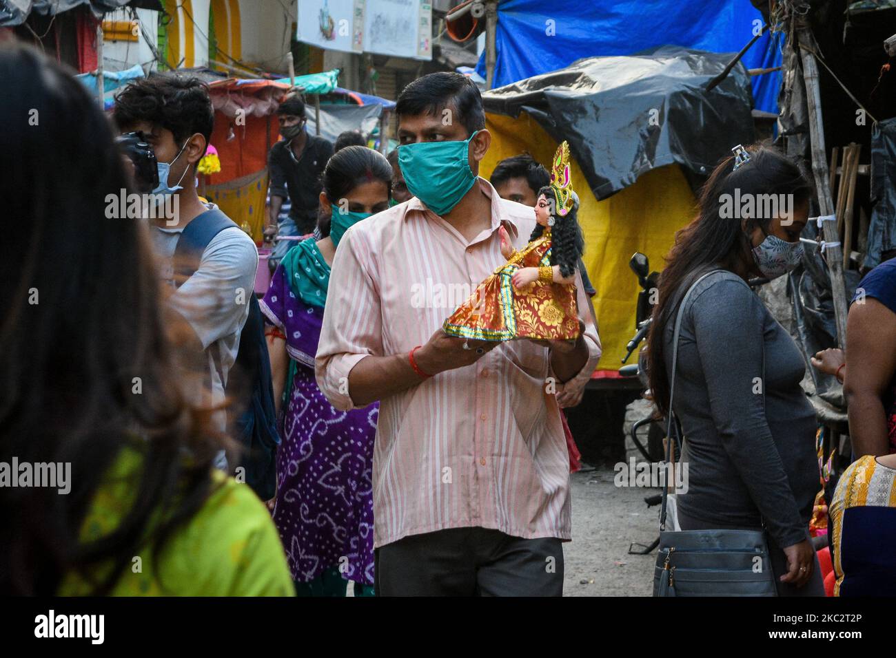 A gentleman wearing mask takes home an idol of Devi Lakshmi ahead of the festival celebration in Kolkata, India, on October 28, 2020. Lakshmi puja is the festival of worshipping goddess Lakshmi , the Hindu goddess of wealth and prosperity. It is celebrated on full moon day after Durga Dashami ( the last day of Durga puja ) . Devotees believe that on the day of Lakshmi puja , the goddess visits her devotees home , bringing with her good wealth and prosperity for the family. Woman's of the family worships Goddess Lakshmi on the day after cleaning their house and drawing Alpona on the floor to in Stock Photo