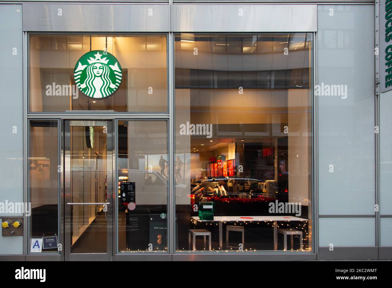 A store front of a Starbucks Coffee shop located in Midtown Manhattan with people walking by. Starbucks Corporation is the world's largest coffeehouse chain, an American multinational cafe chain with headquarters in Seattle Washington. NYC, United States of America on February 2020 (Photo by Nicolas Economou/NurPhoto) Stock Photo